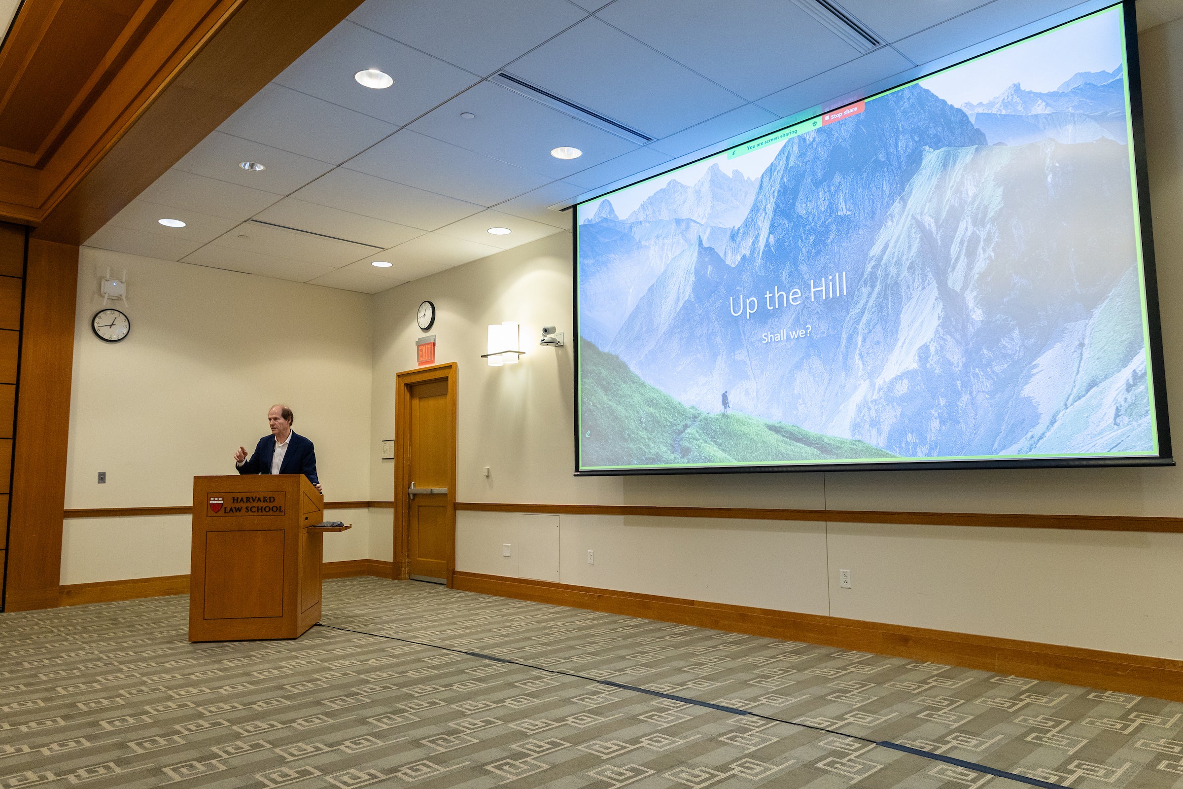 Cass Sunstein speaks in front of a large projection.