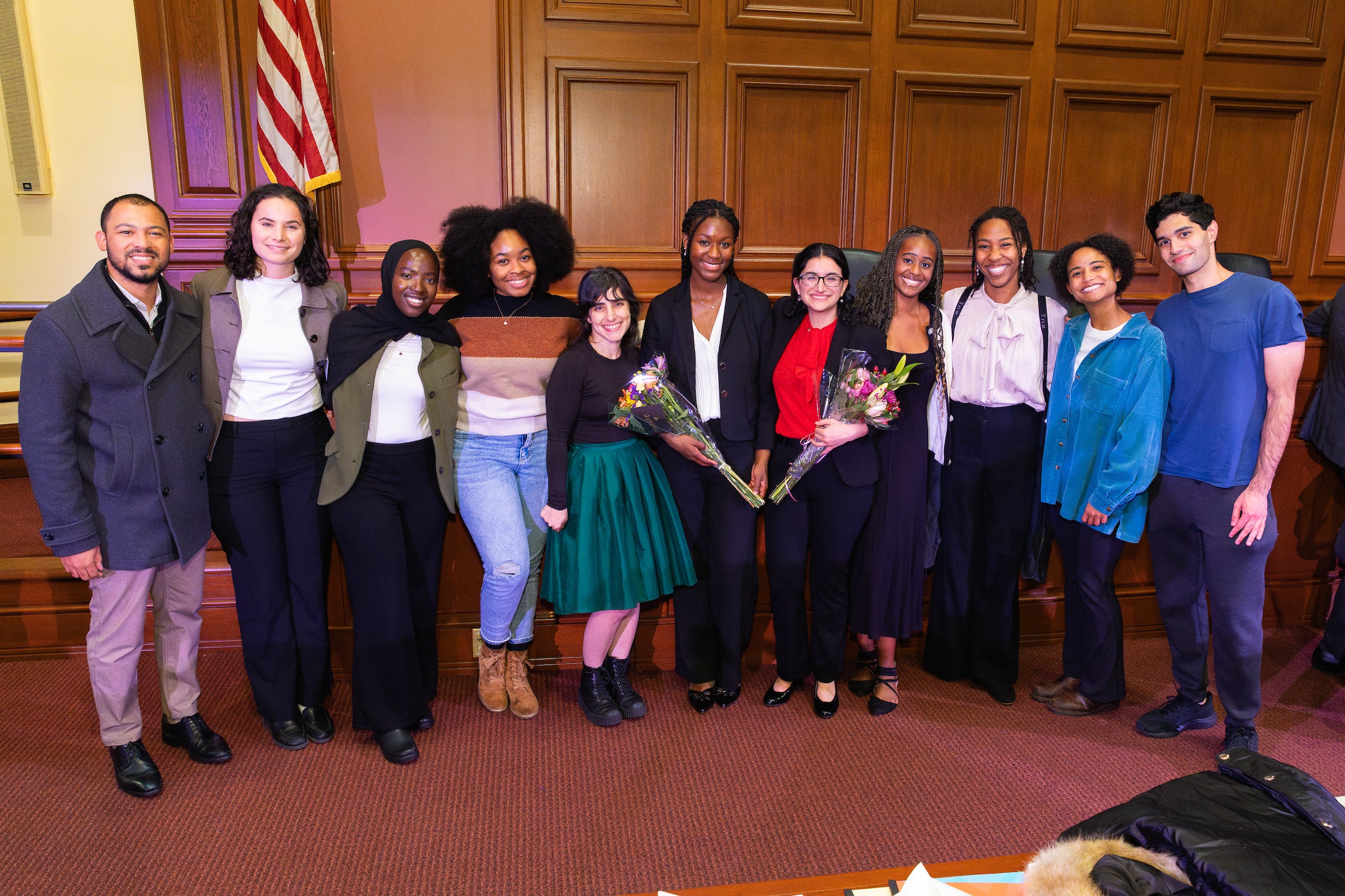 A large group of students gather in front of the courtroom for a photo with an Ames team member.