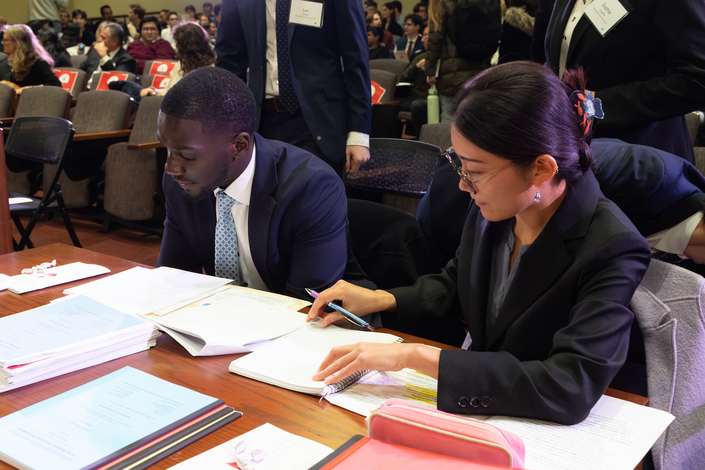 Two students sitting at a table looking over papework.