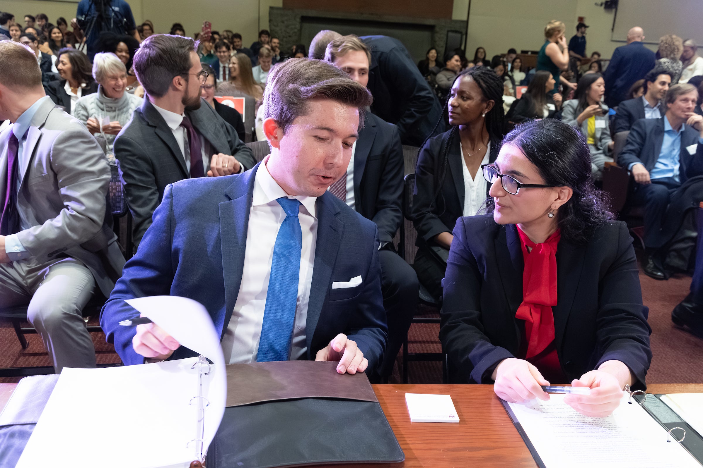 Two students sitting at a table review paperwork.
