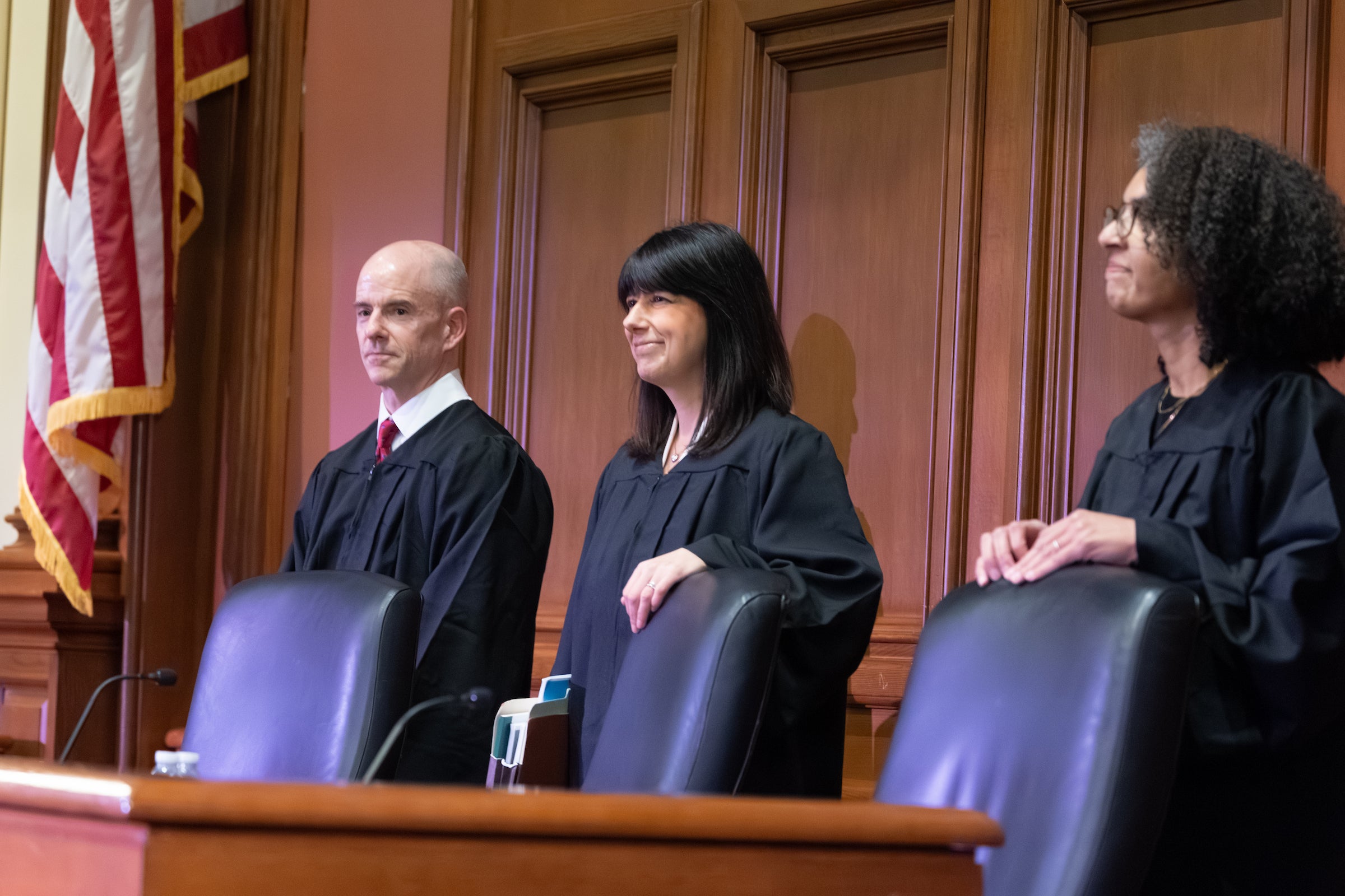 Three judges standing beside the bench.