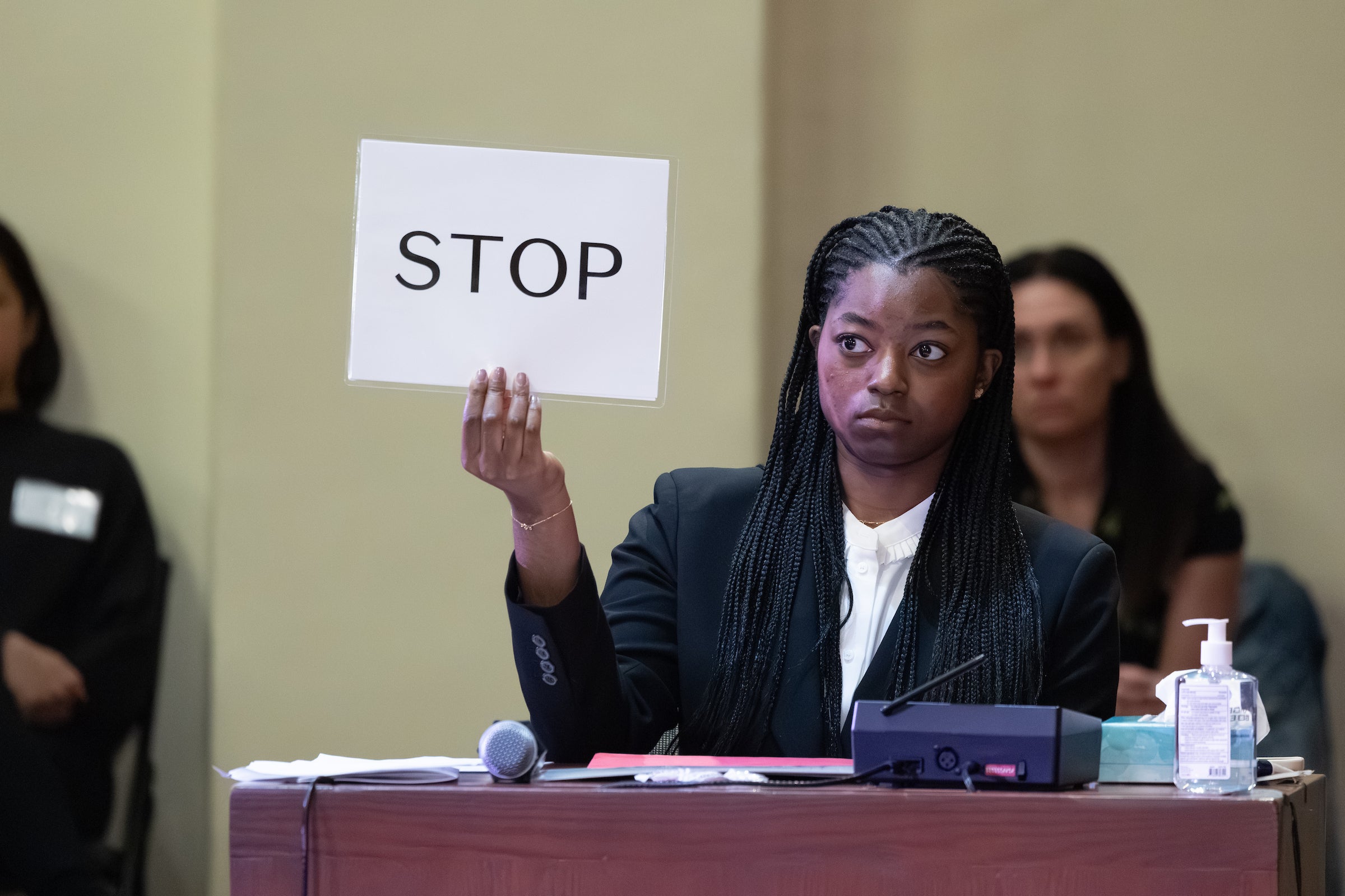 A woman holds a sign that sa.ys 