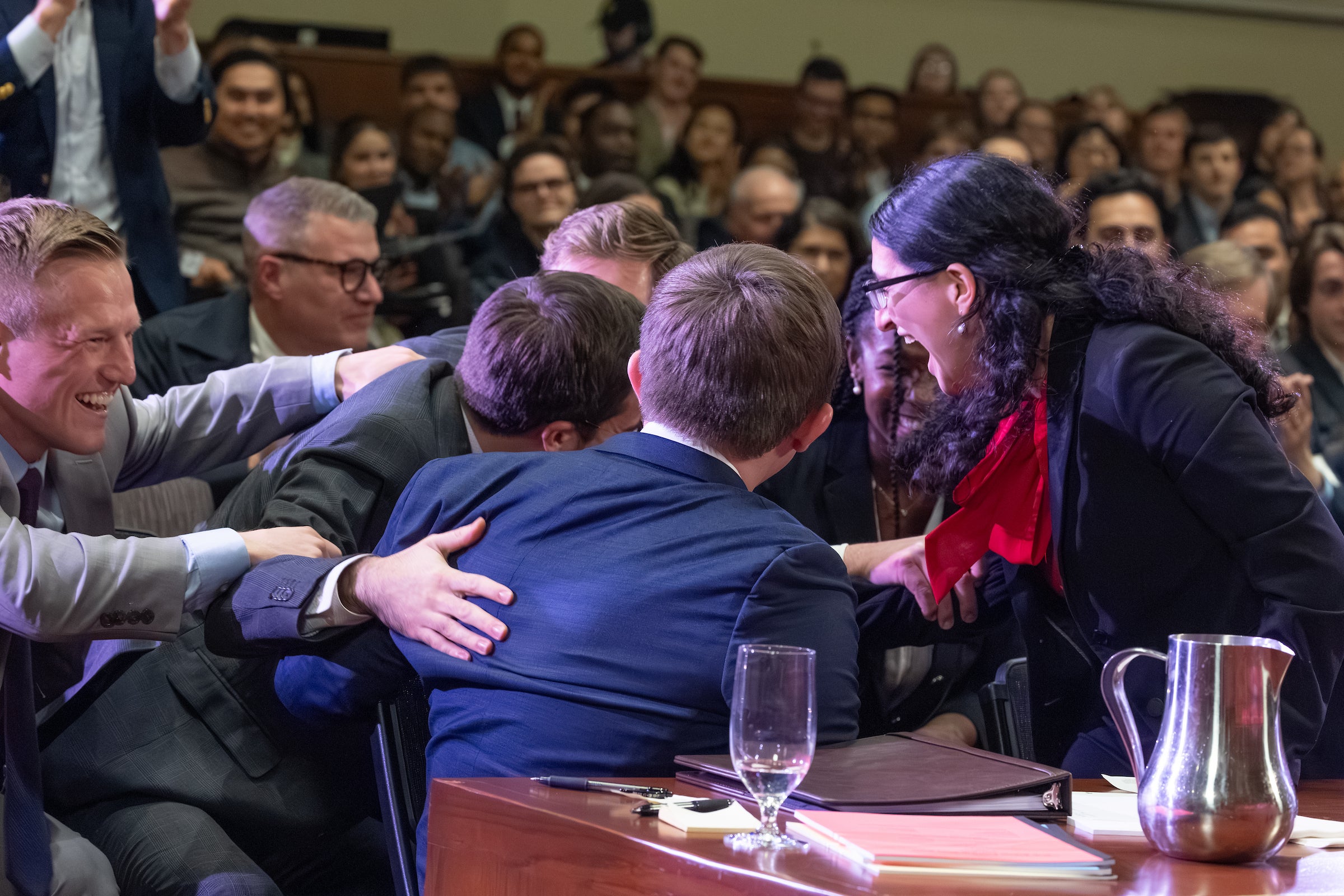 Several students on a team gather for a group hug and share their excitement following oral arguments.