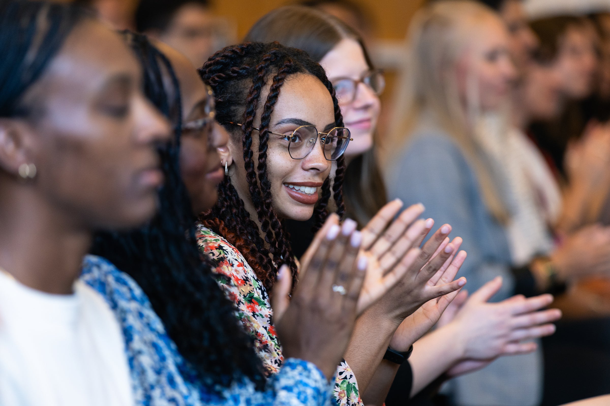 Students sitting at an event clapping.