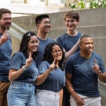 A group of students pose on the steps of a building during orientation.