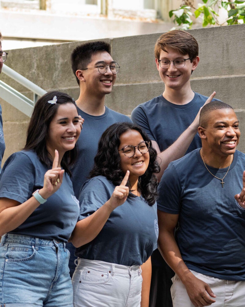 A group of students pose on the steps of a building during orientation.