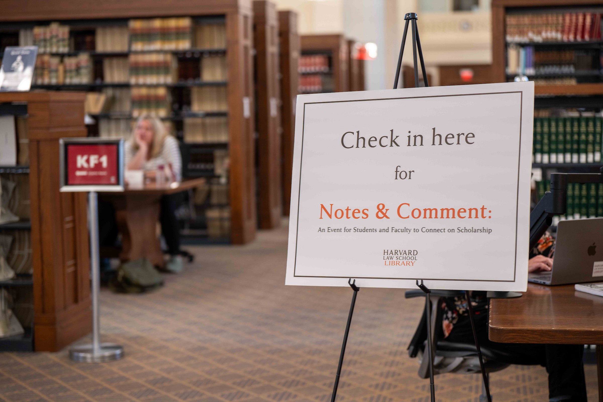 A sign posted in a library says Check in here for Notes & Comment.