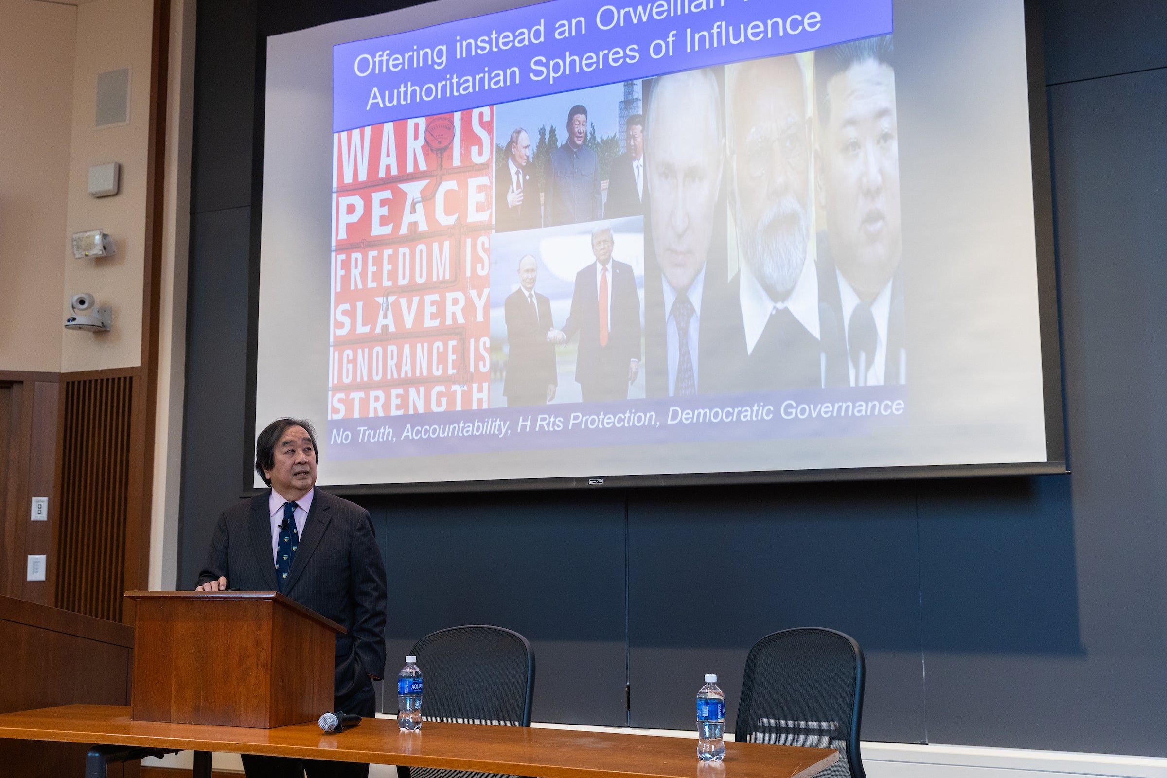Harold Hongju Koh in front of a screen illustrating 