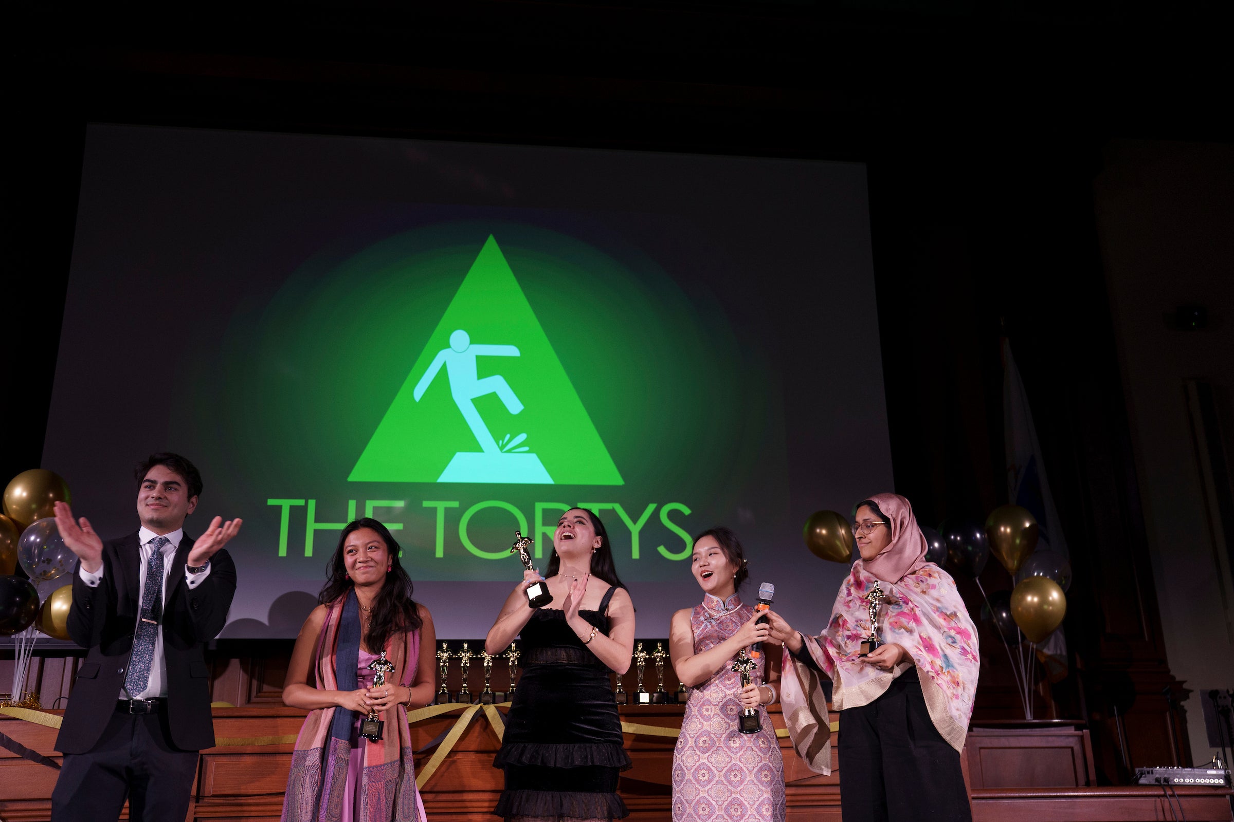 Students stand on a stage holding awards.