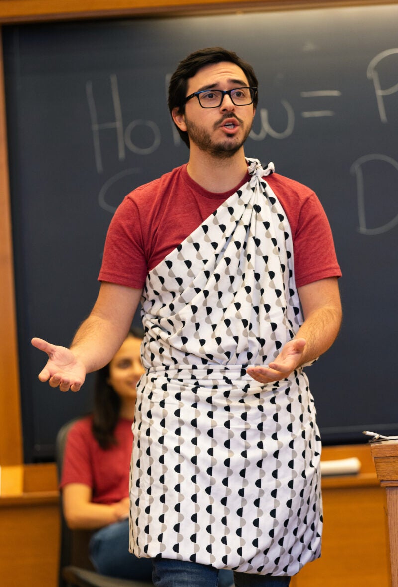 A student in a patterned toga argues on behalf of Socrates.
