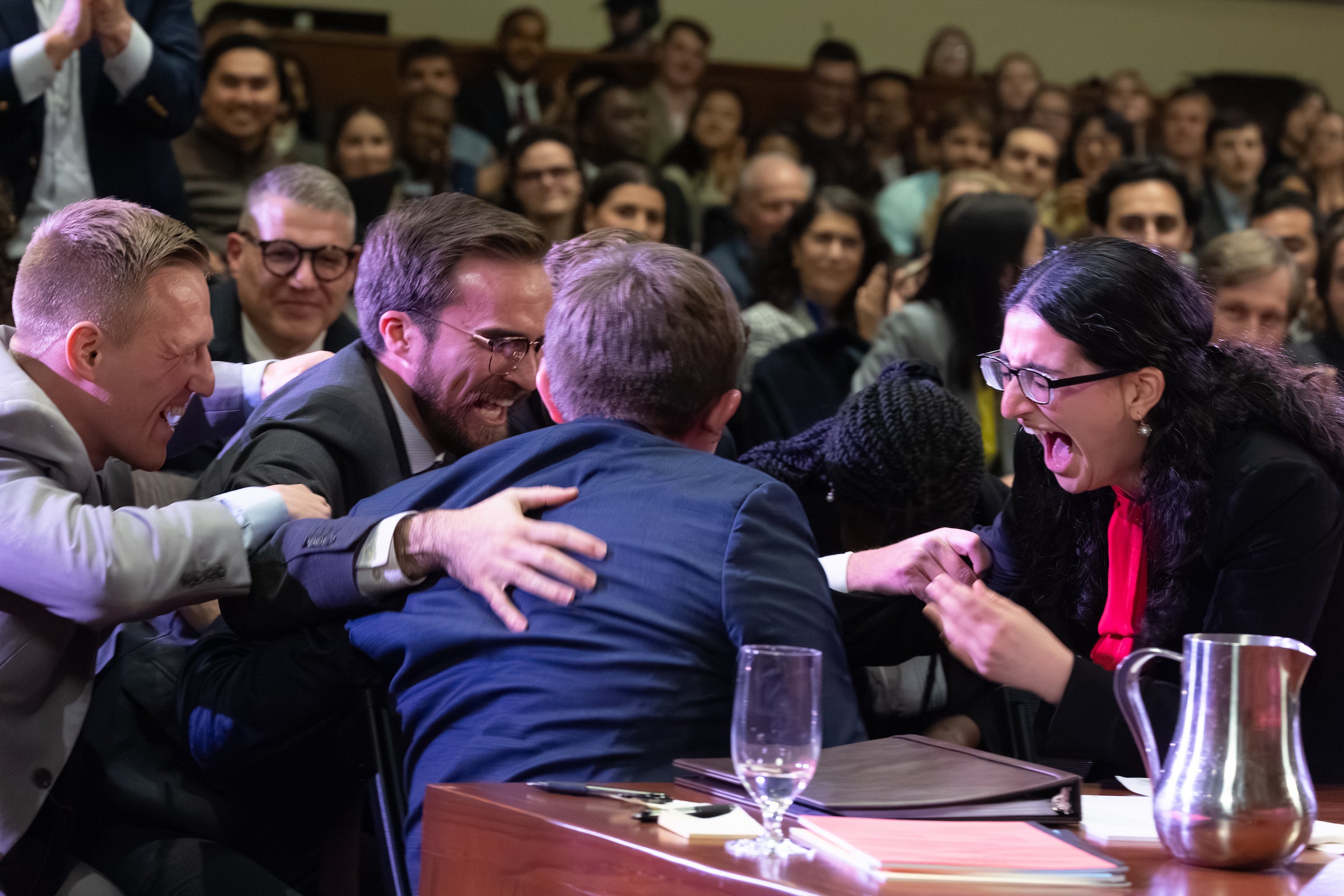 Students sitting at a table congratulate each other.