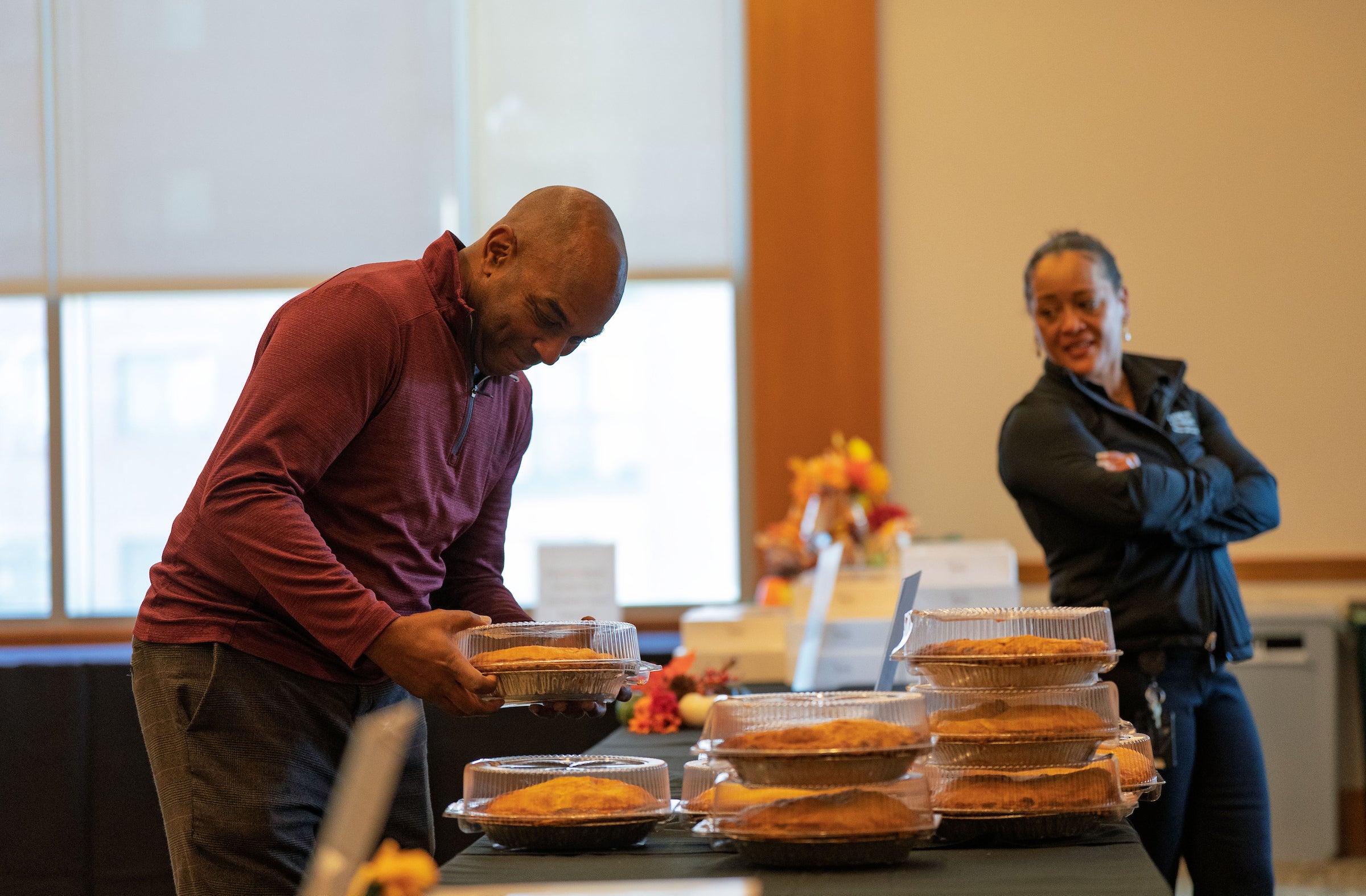 A man picks up a pie from a table of pies.