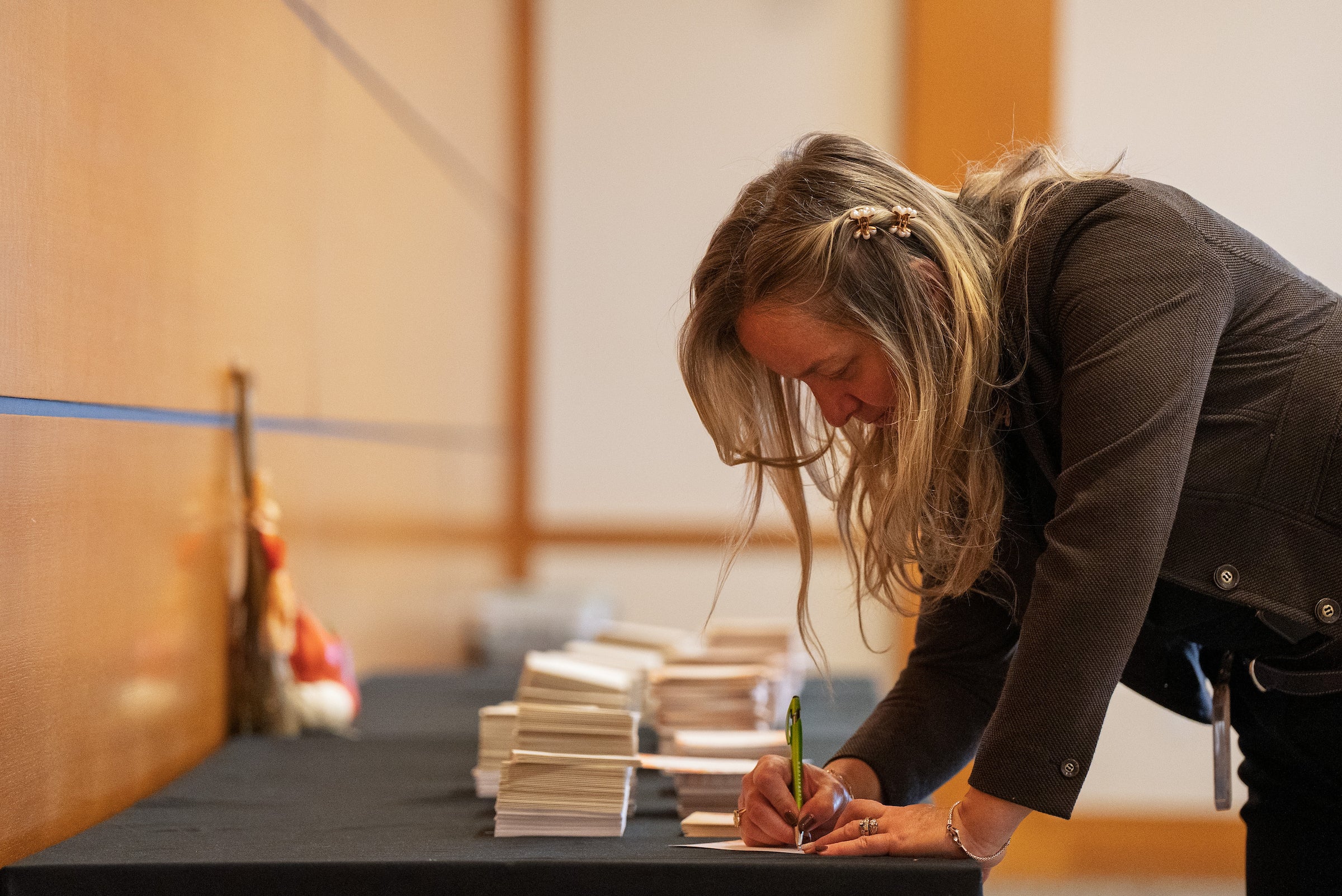 A woman is signing a card on a table.