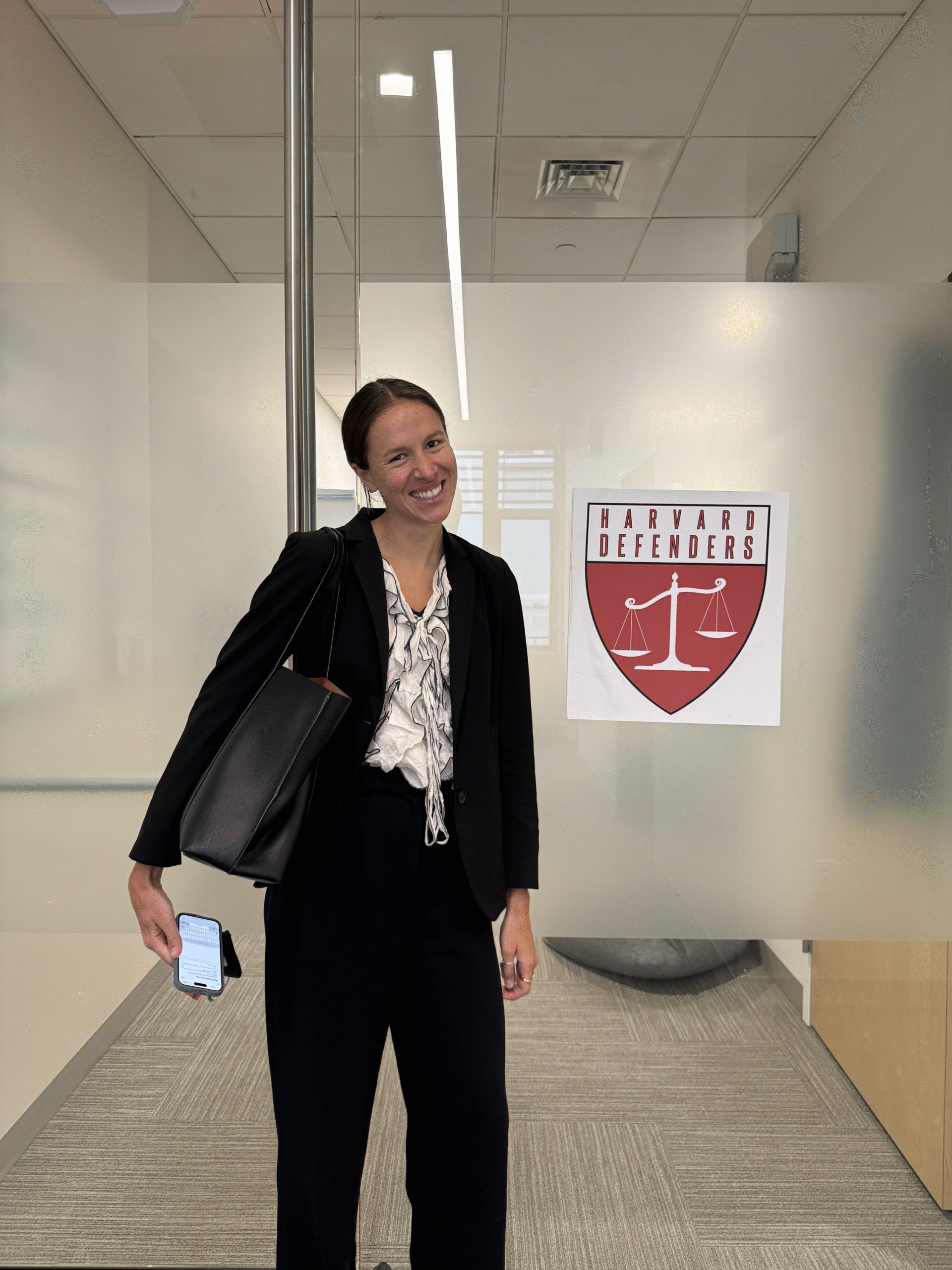 Ava stands next to a Harvard Defenders sign