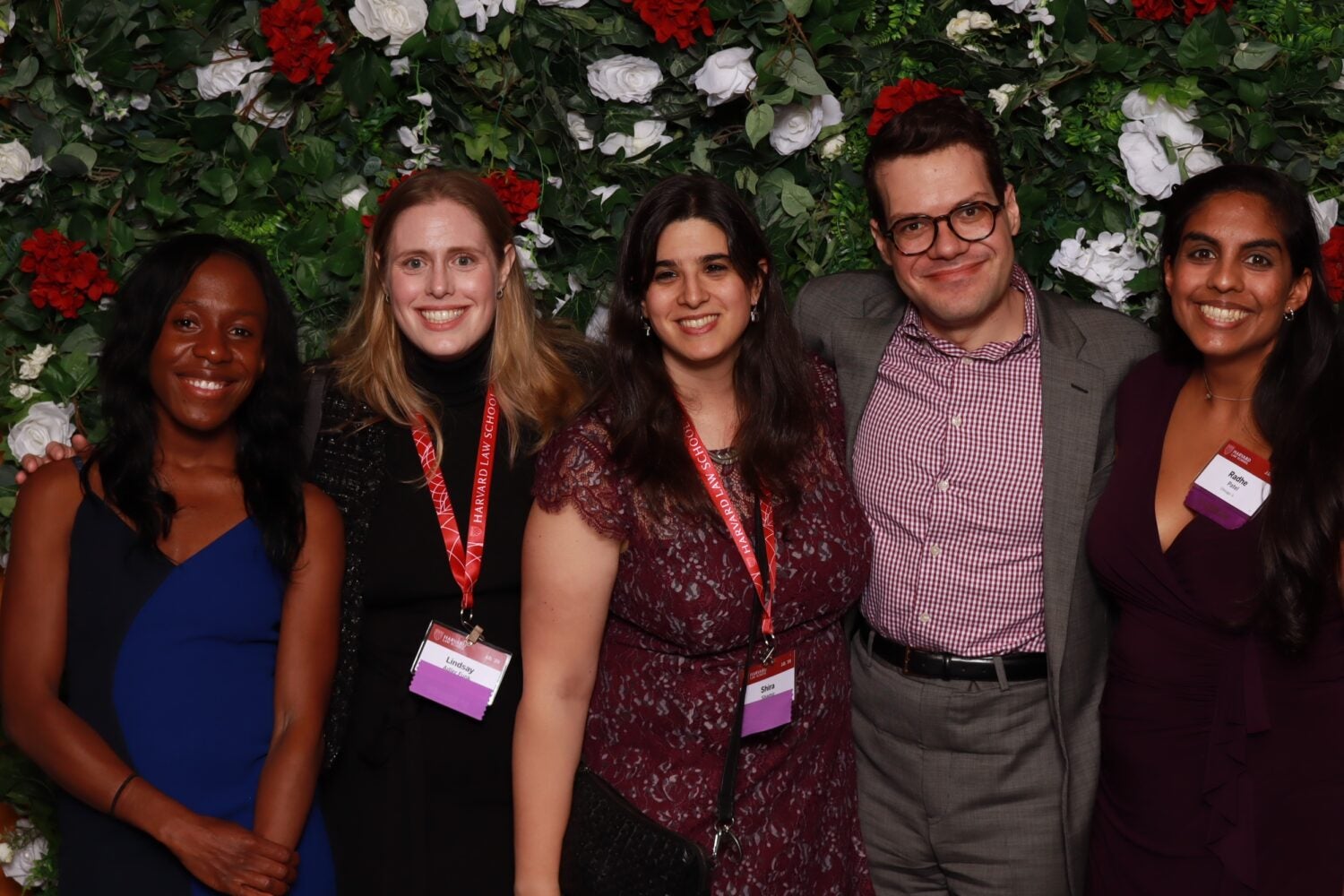 Alumni posing together against a flower backdrop