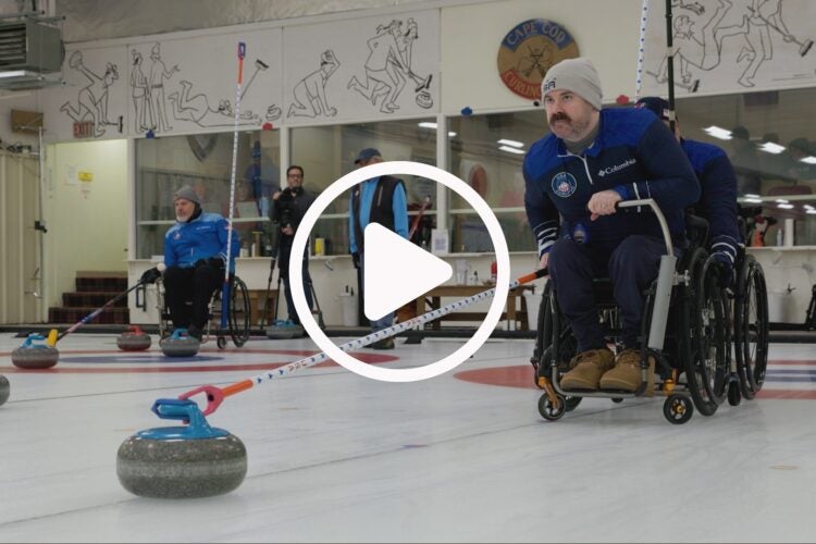 Man in wheelchair curling with a video play button.
