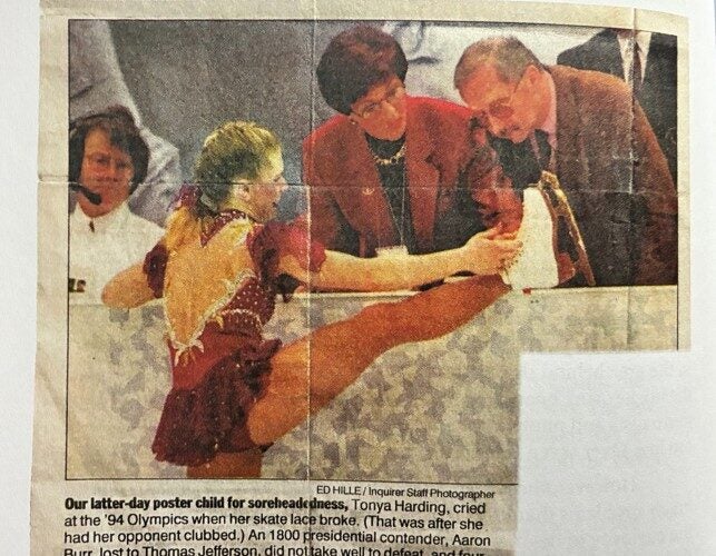 Man looking at an ice skater's skate during competition