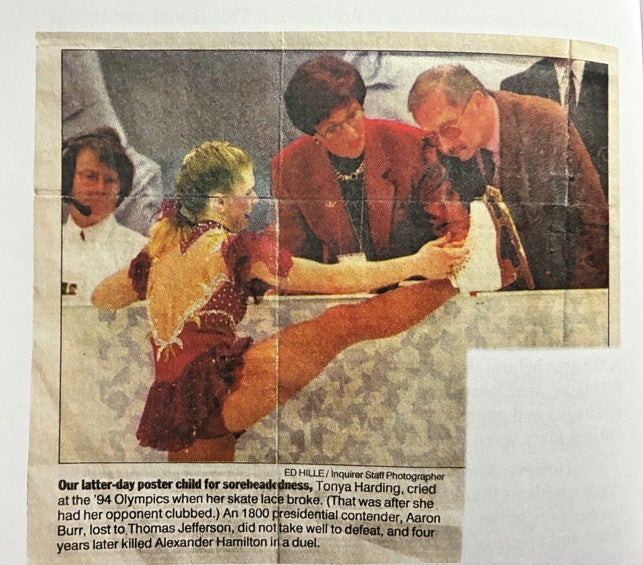 Man looking at an ice skater's skate during competition