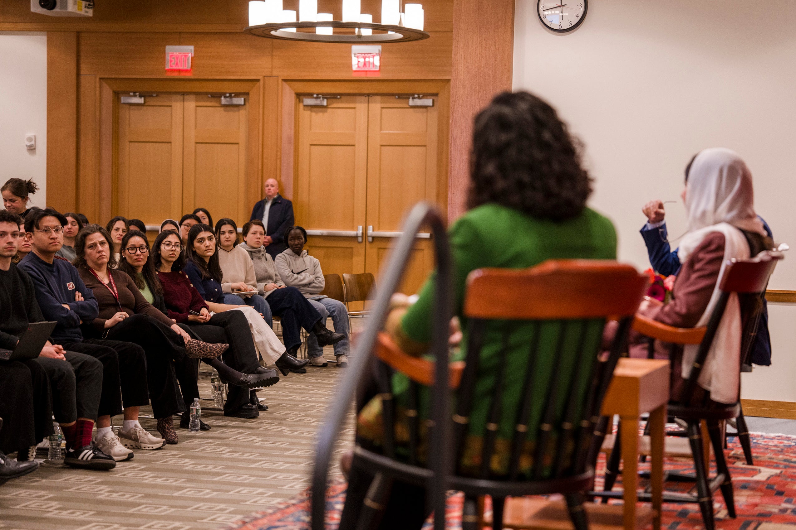 A reverse angle of panelists Malala Yousafzai and Gaisu Yari with audience members listening intently.