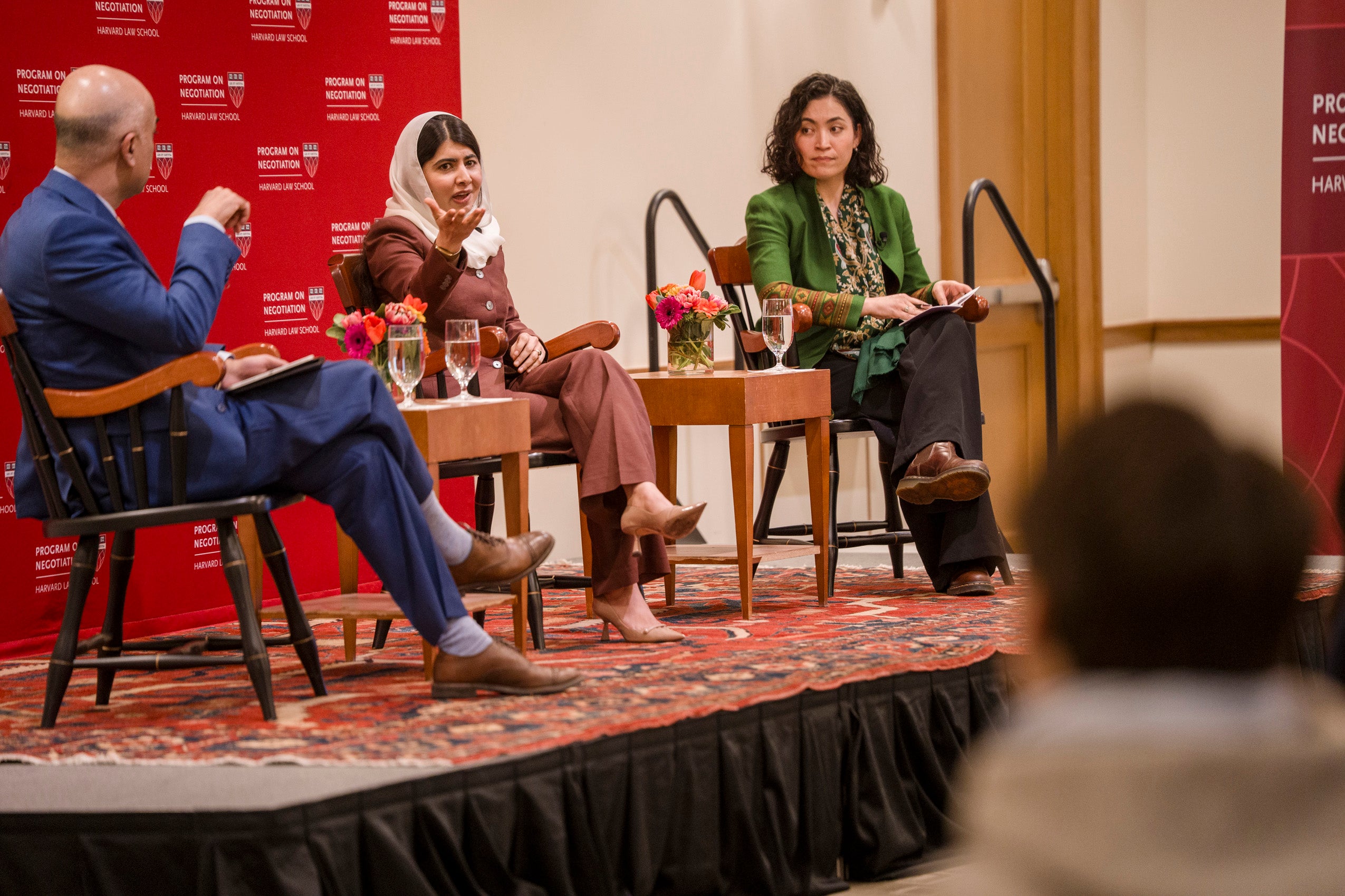 Malala Yousafzai speaks to the audience as Guhan Subramanian and Gaisu Yari listen.