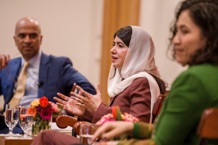 Malala Yousafzai speaking while Guhan Subramanian and Gaisu Yari listen.