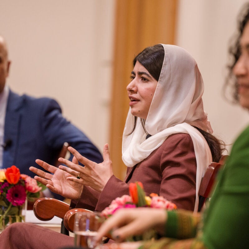 Malala Yousafzai speaking while Guhan Subramanian and Gaisu Yari listen.