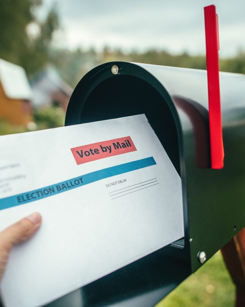 Mail in ballot being put in a mailbox.