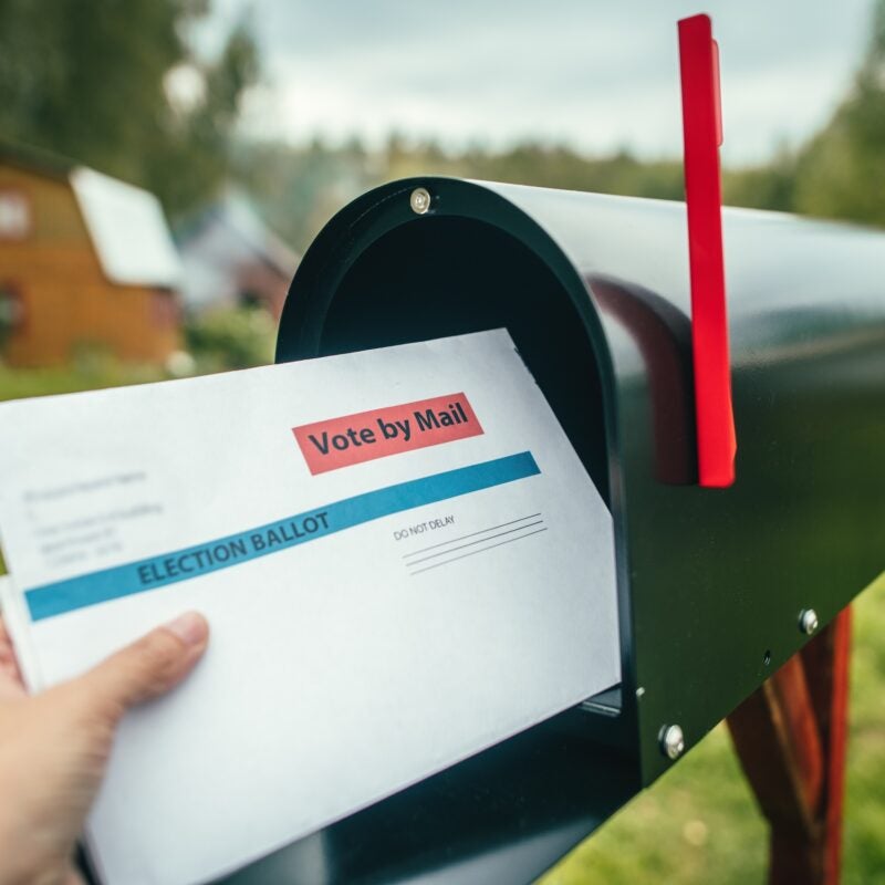 Mail in ballot being put in a mailbox.