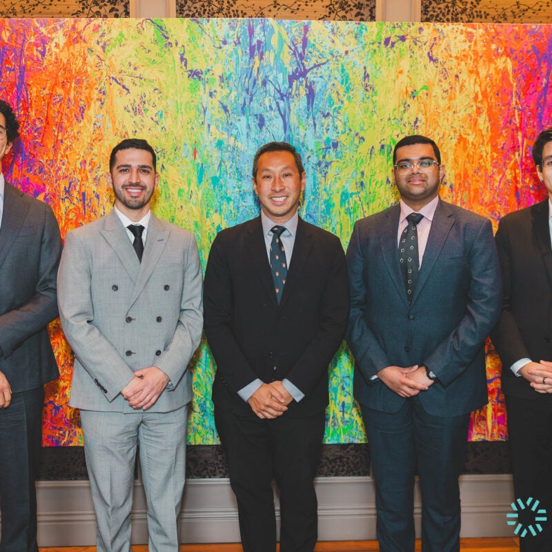 four men posing with Professor Mark Wu in front of a painting