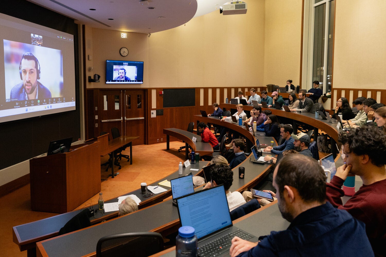 A view of a classroom with a speaker on the screen.