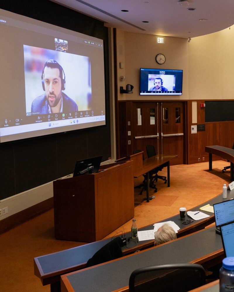 A view of a classroom with a speaker on the screen.