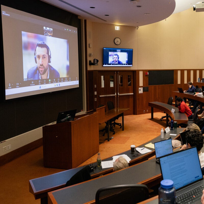 A view of a classroom with a speaker on the screen.
