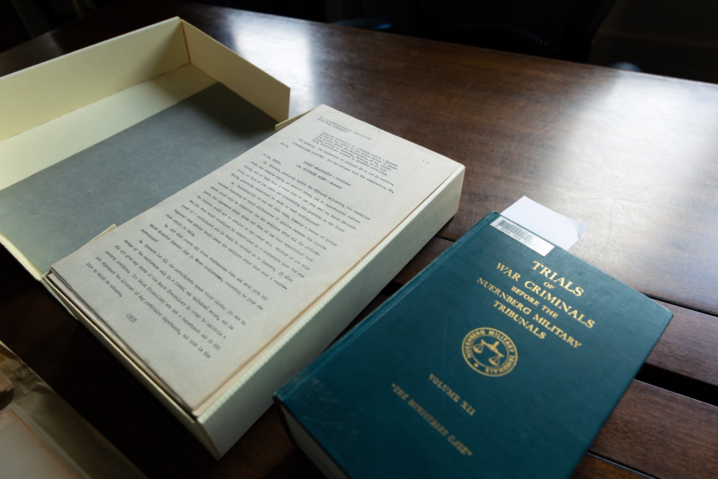An archival box with papers from the Nuremberg Collection next to a book entitled Trials of War Criminals.