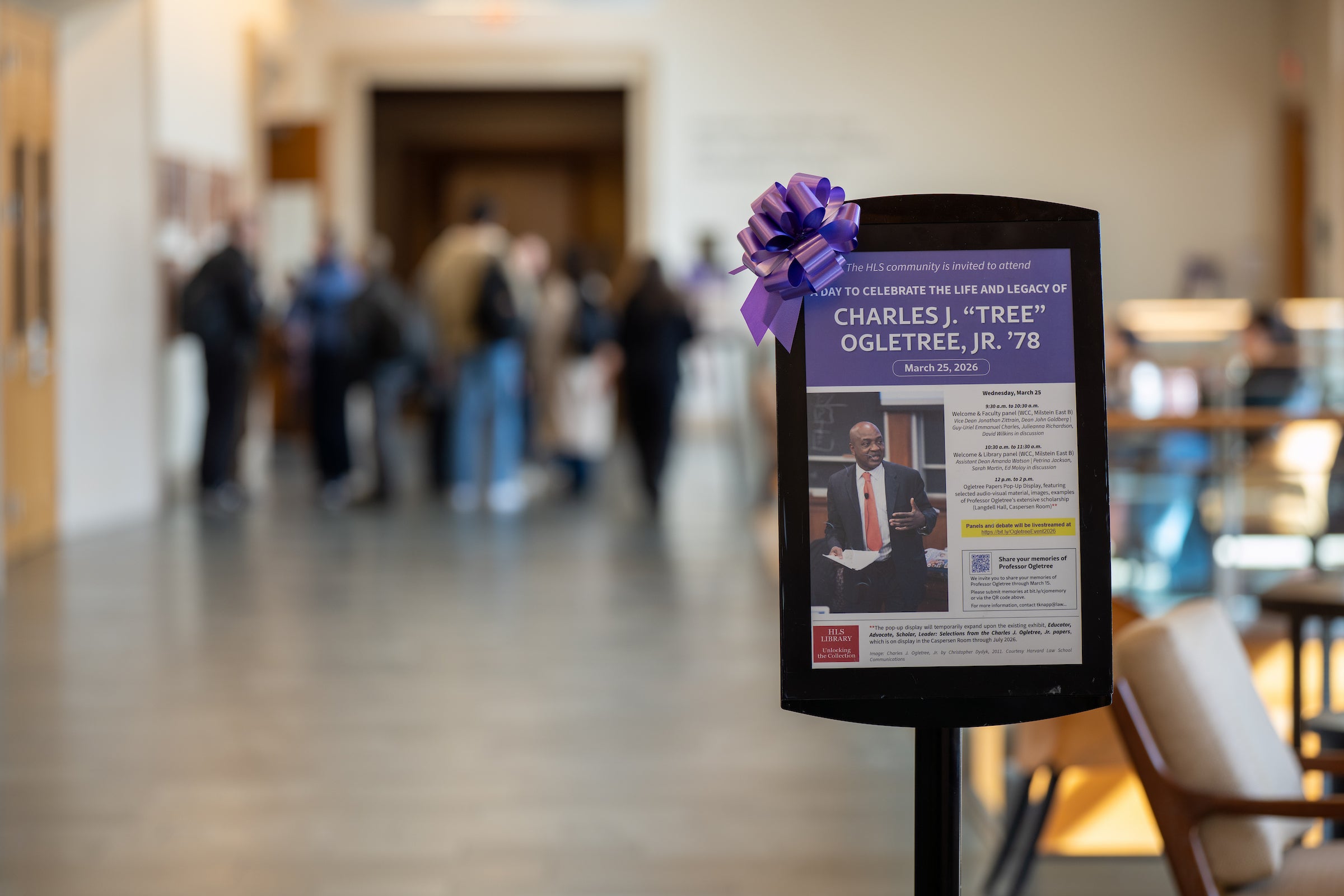 Event poster displayed in a stand with a purple bow on it.