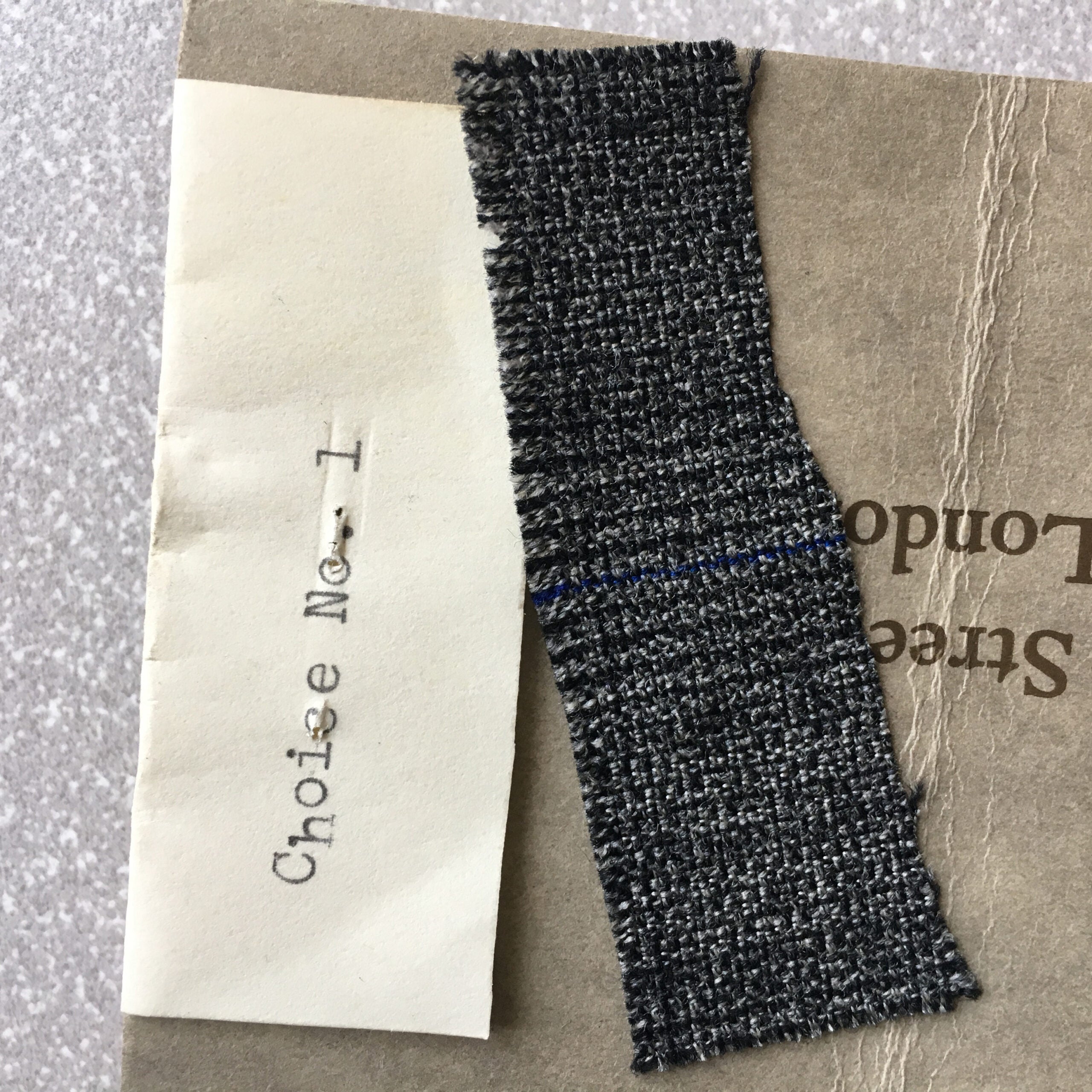 Close-up of a piece of cream paper with typescript “Choice No. 1” and a swatch of fabric.