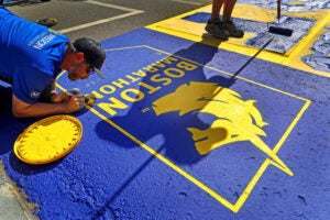 A work crew paints the starting line for the upcoming 130th Boston Marathon.
