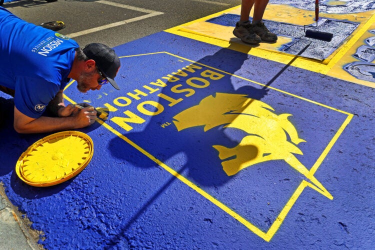 A work crew paints the starting line for the upcoming 130th Boston Marathon.