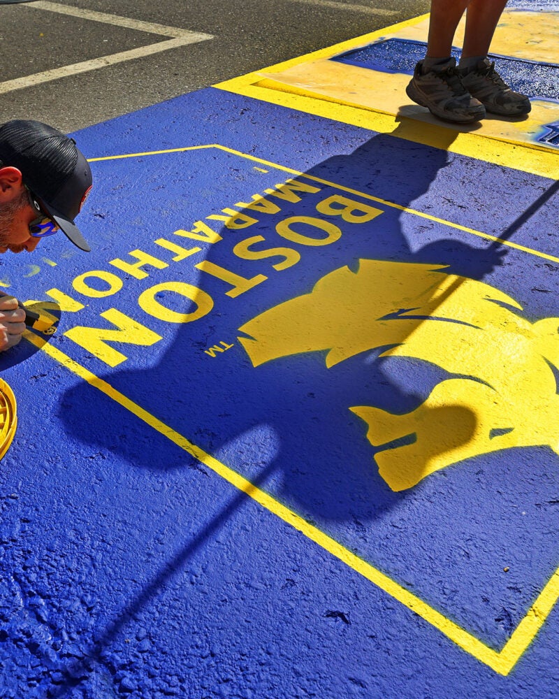 A work crew paints the starting line for the upcoming 130th Boston Marathon.