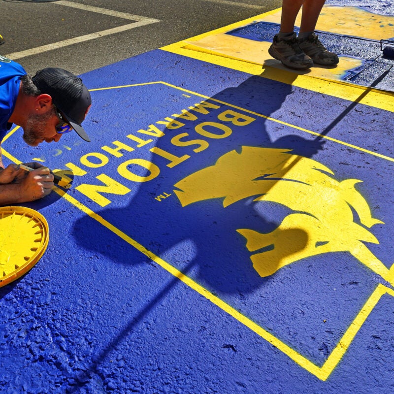A work crew paints the starting line for the upcoming 130th Boston Marathon.