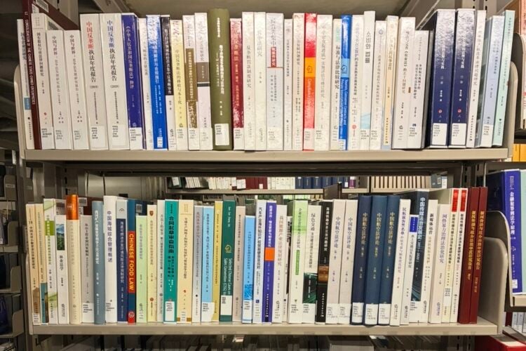 Spines of Chinese legal studies books on a library book shelf.
