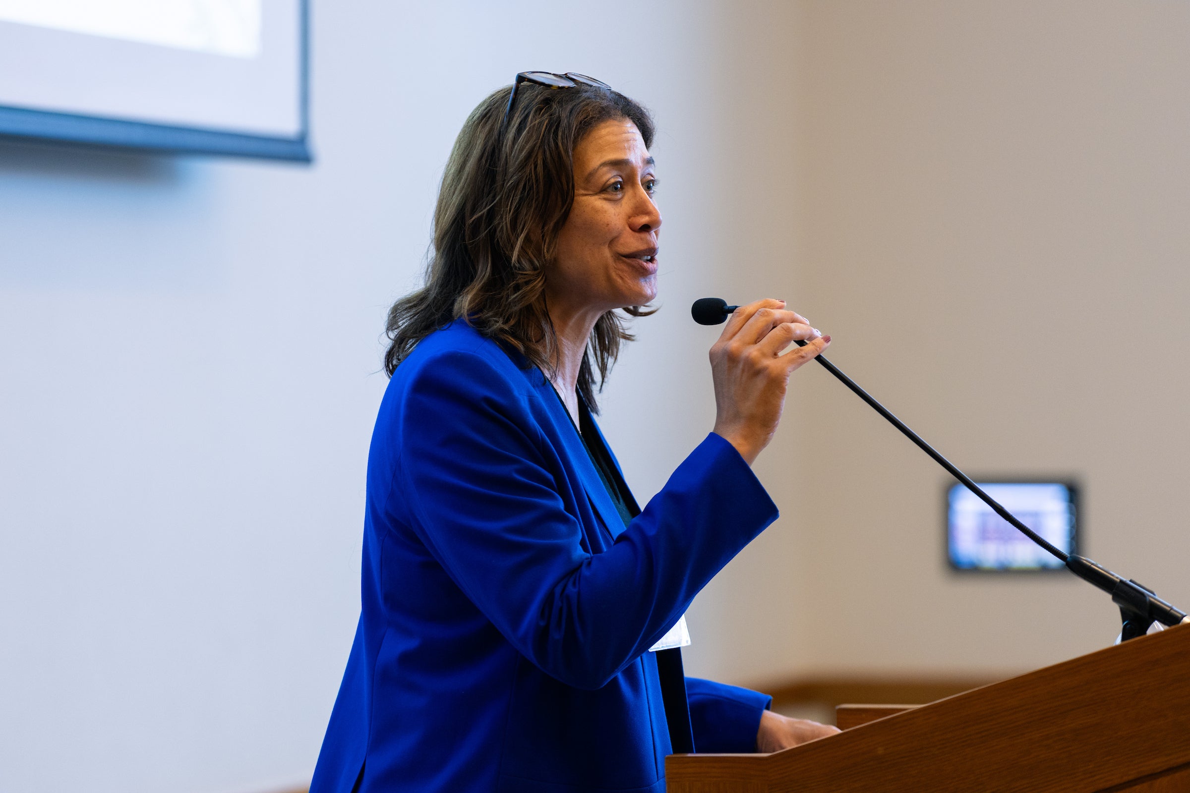 Monica Monroe stands behind a podium and speaks into a microphone.