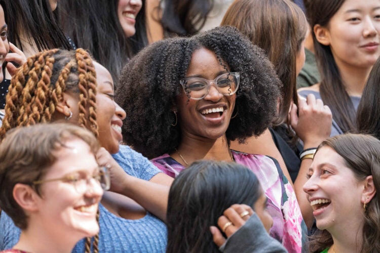 A closeup of several students in a larger group photo, smiling and talking with each other.