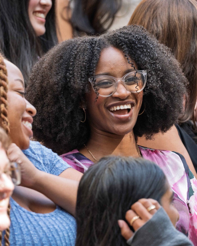 A closeup of several students in a larger group photo, smiling and talking with each other.
