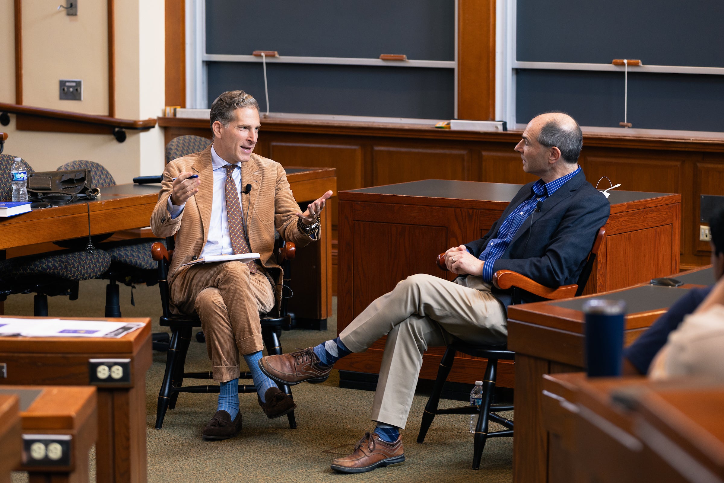 Noah Feldman and Richard Primus, seated next to each other, engage in conversation in a classroom.