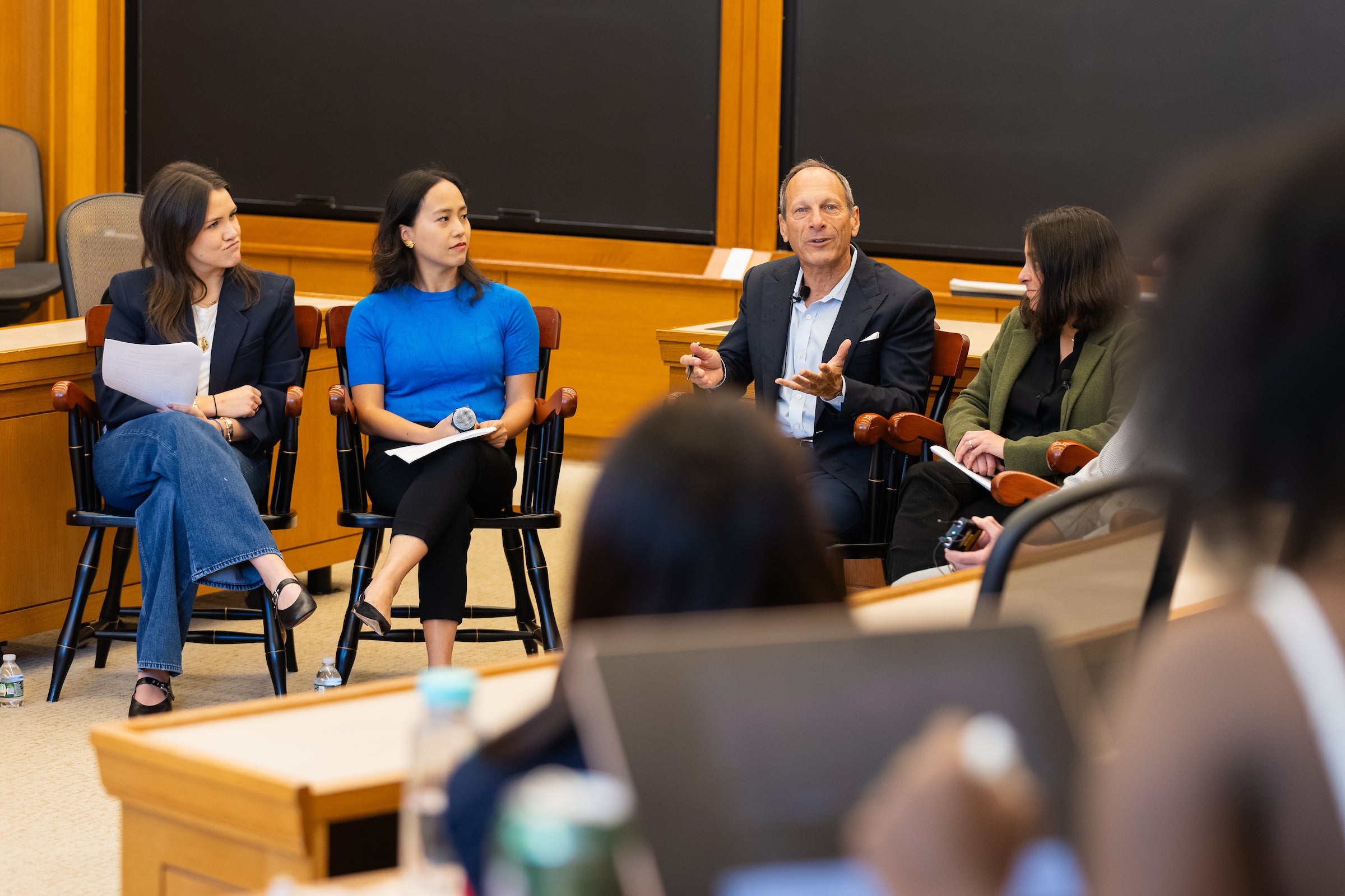 A panel of people converse in a classroom.