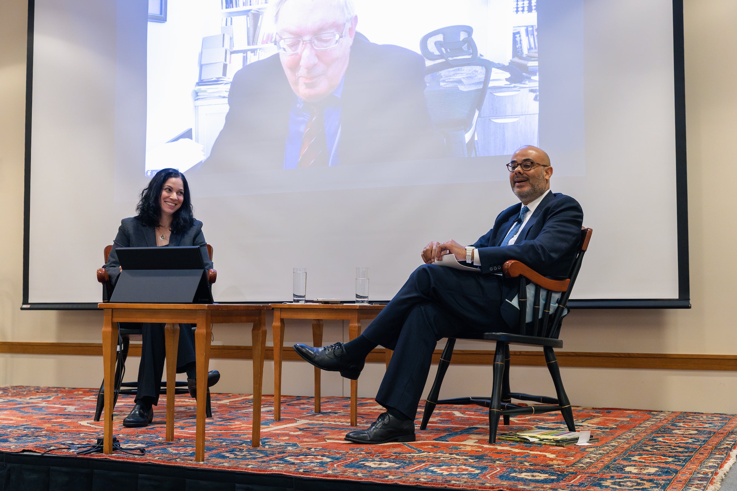 Professor Laura Weinrib and Justin Driver sit on a stage in conversation, with Douglas Laycock on the screen behind them.