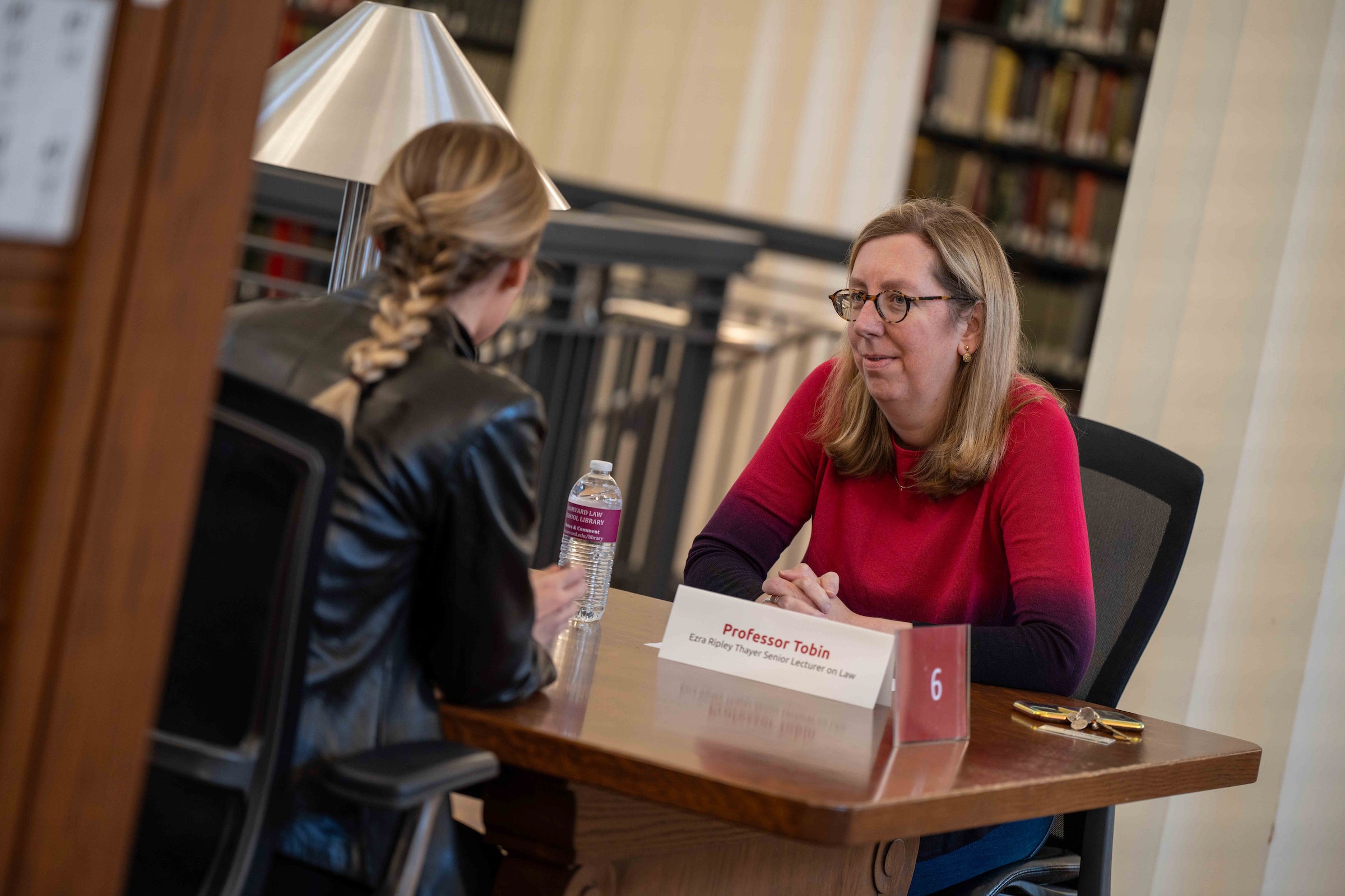 A student and a faculty member speaking with each other in the library.