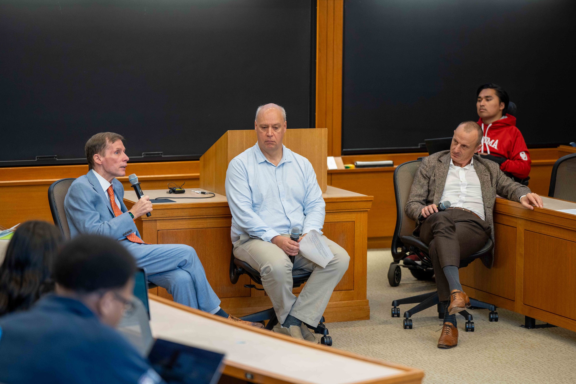 Three men speaking in a classroom.