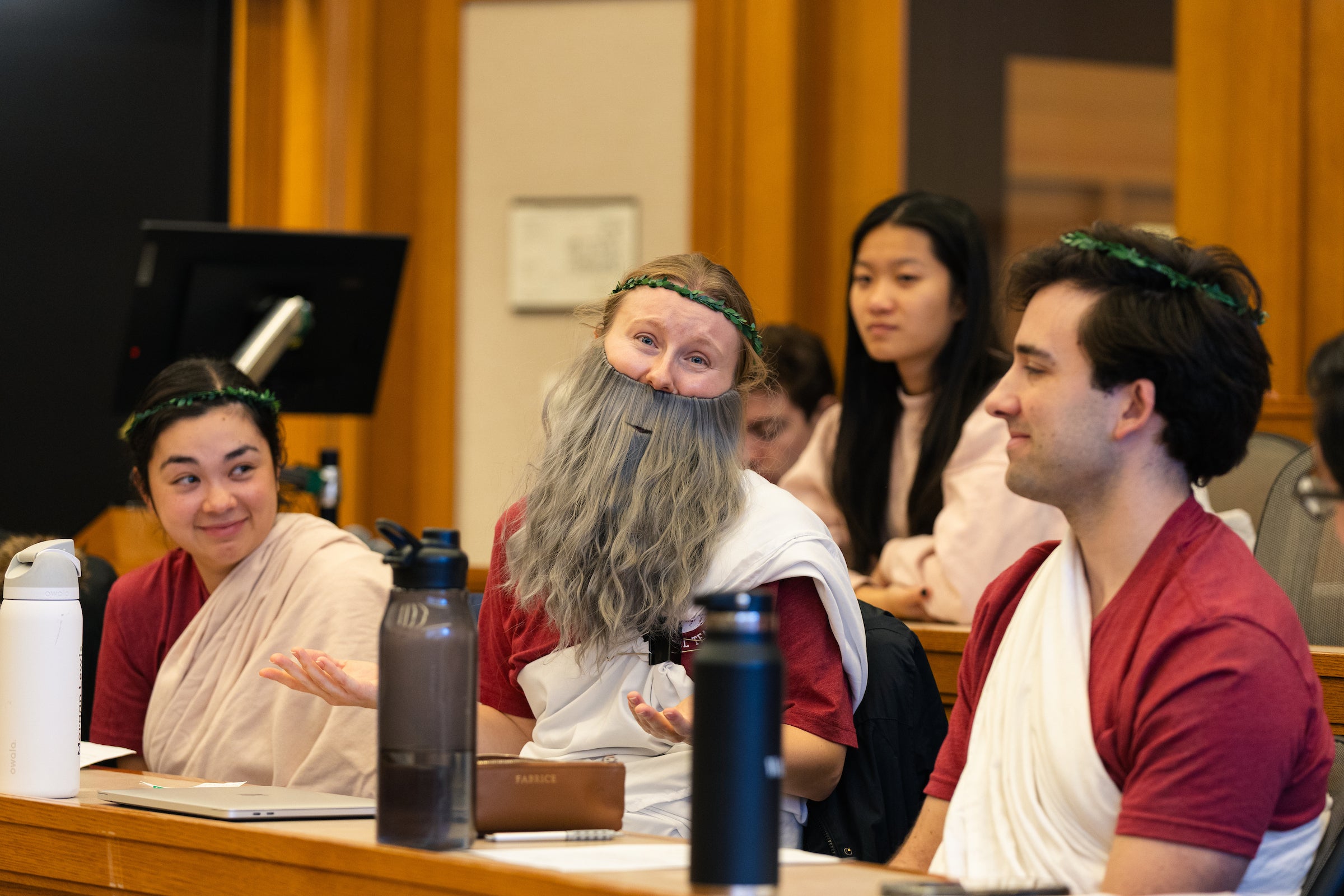 Students in Ancient Greek costumes speak in a classroom.