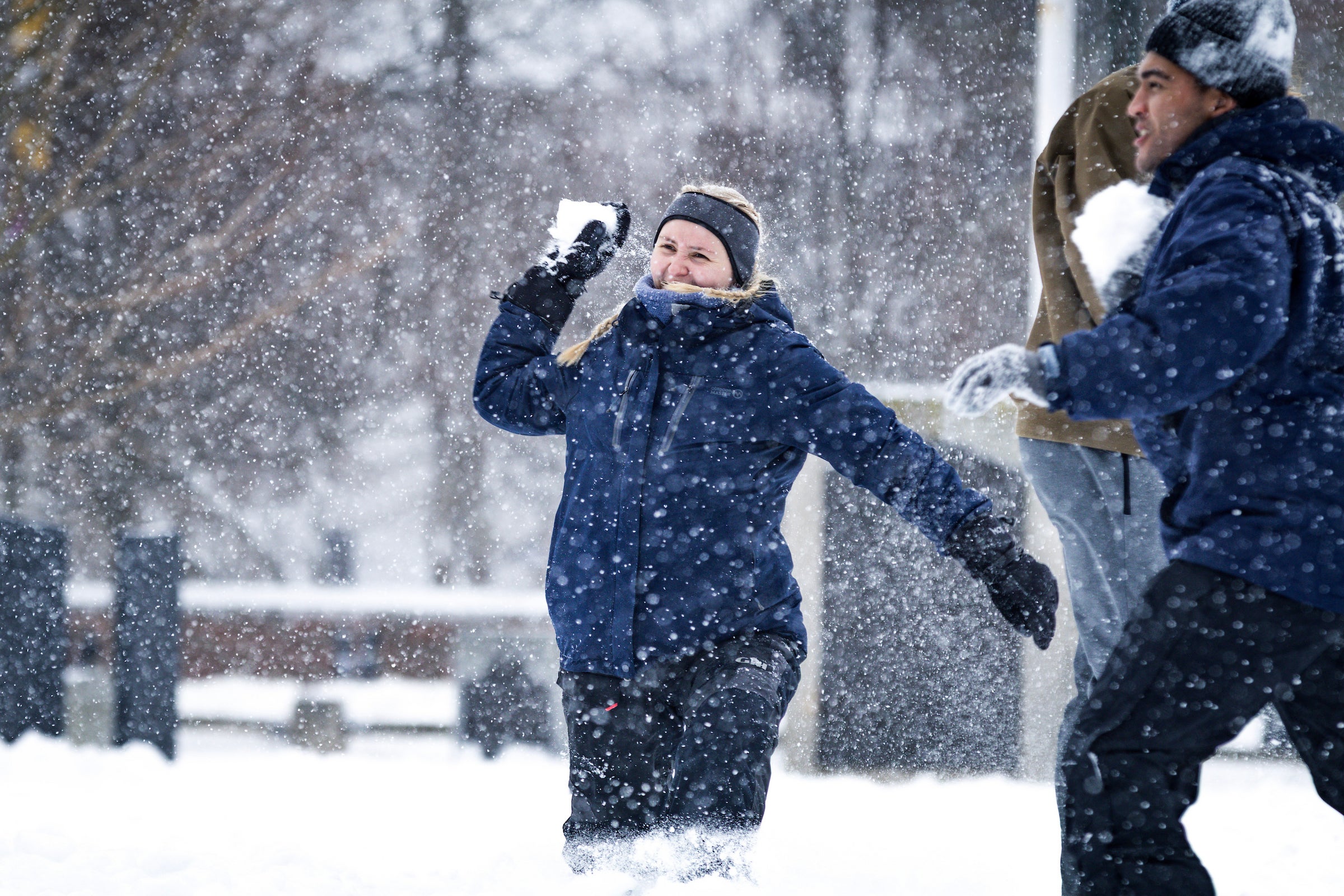Two students throw snowballs at each other during a snowstorm.